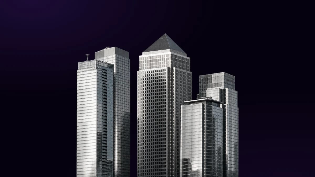 Black-and-white financial buildings rising from the bottom edge against a dark background.