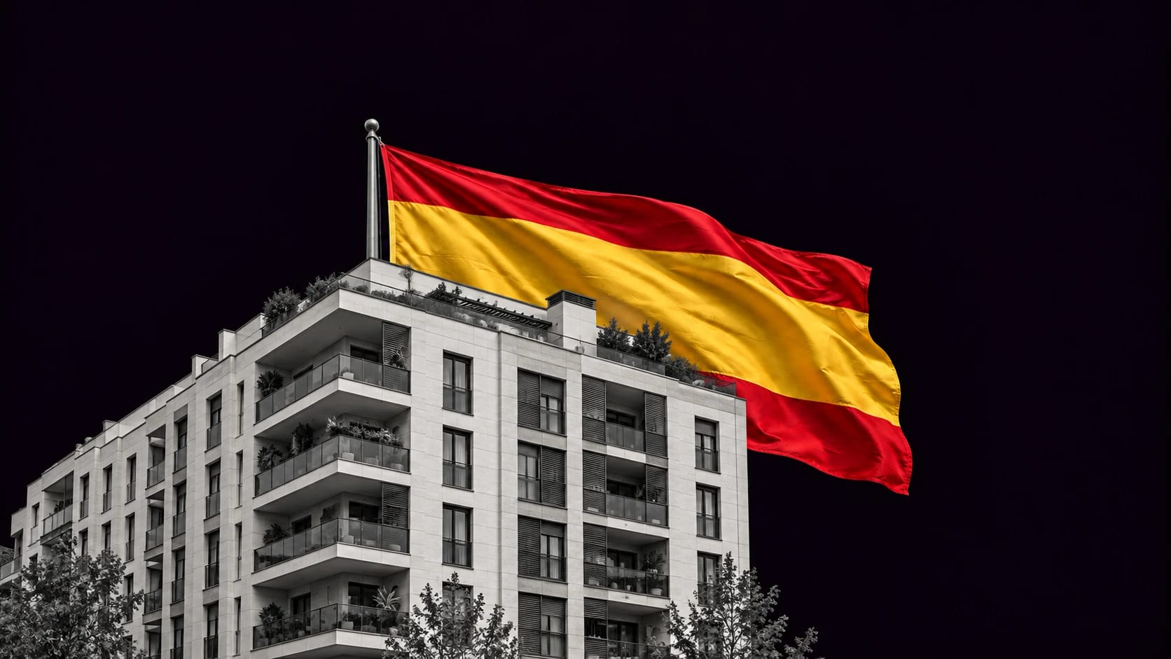 Edificio residencial contemporáneo con terrazas junto a una bandera española de tela sobre fondo oscuro