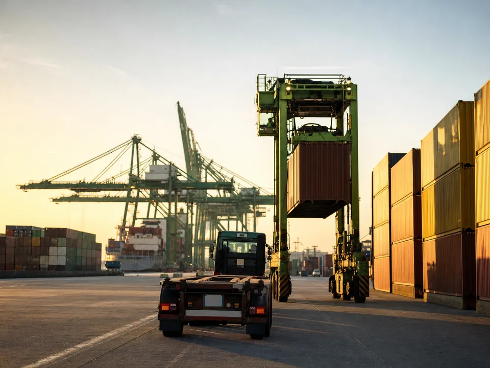 Truck seen from behind waiting beside stacks of containers at a port of Antwerp terminal, container release with blockchain in Belgium