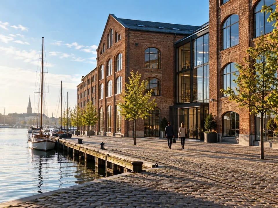 Brick office building on Copenhagen harbour with people seen from behind on the quay, fund managers with blockchain in Denmark