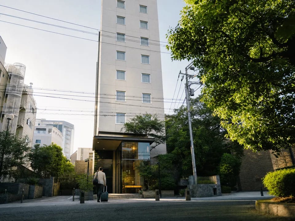 Facade of a business hotel in central Kobe with a traveller walking in with a suitcase, tokenized real estate trusts with blockchain in Japan