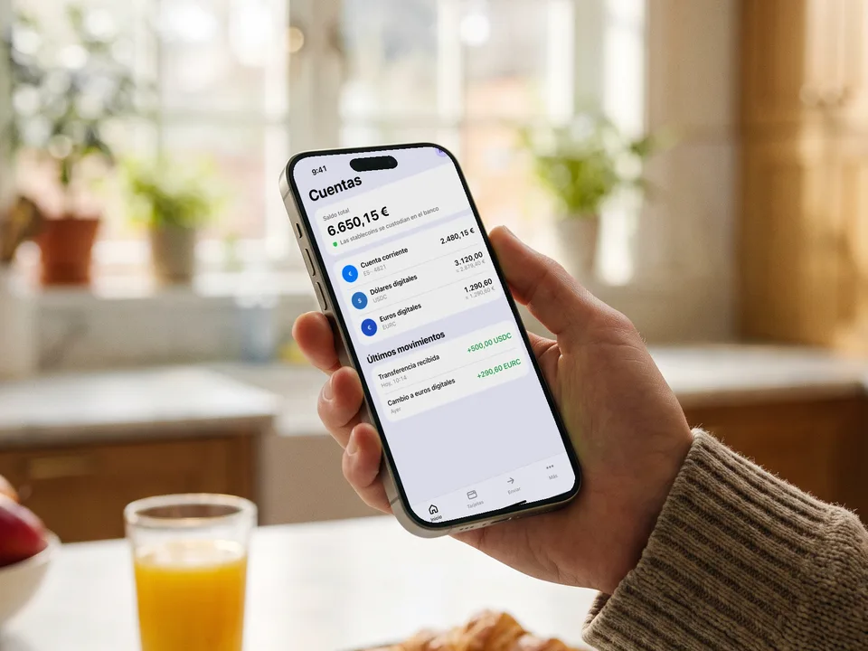 Móvil con la app de un banco que muestra cuentas en euros, USDC y EURC, wallet con stablecoins