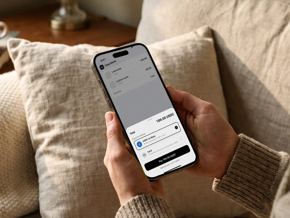 Phone showing an online shop checkout with USDC payment selected, stablecoin payments
