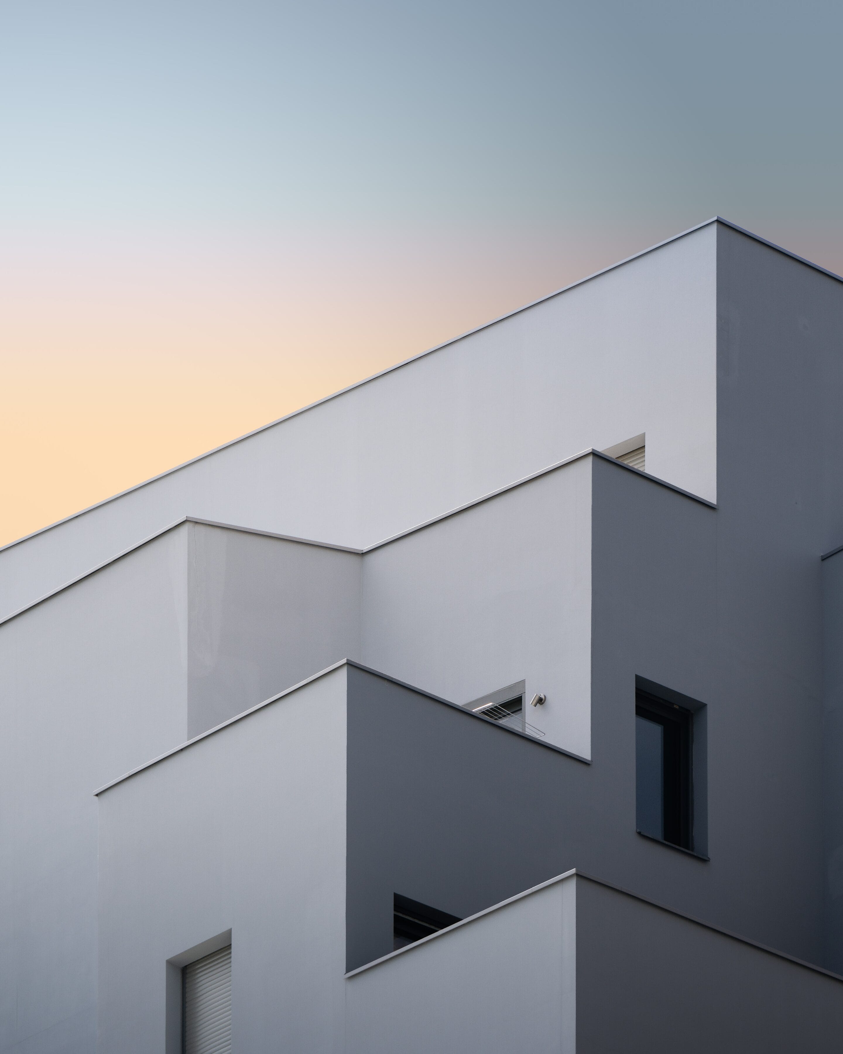 Fachada de volúmenes blancos de un edificio residencial de obra nueva al atardecer