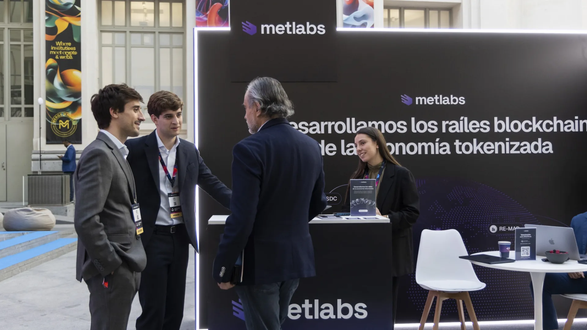 Pablo Gómez and a Metlabs colleague talking with a visitor at the company’s stand at MERGE Madrid 2026